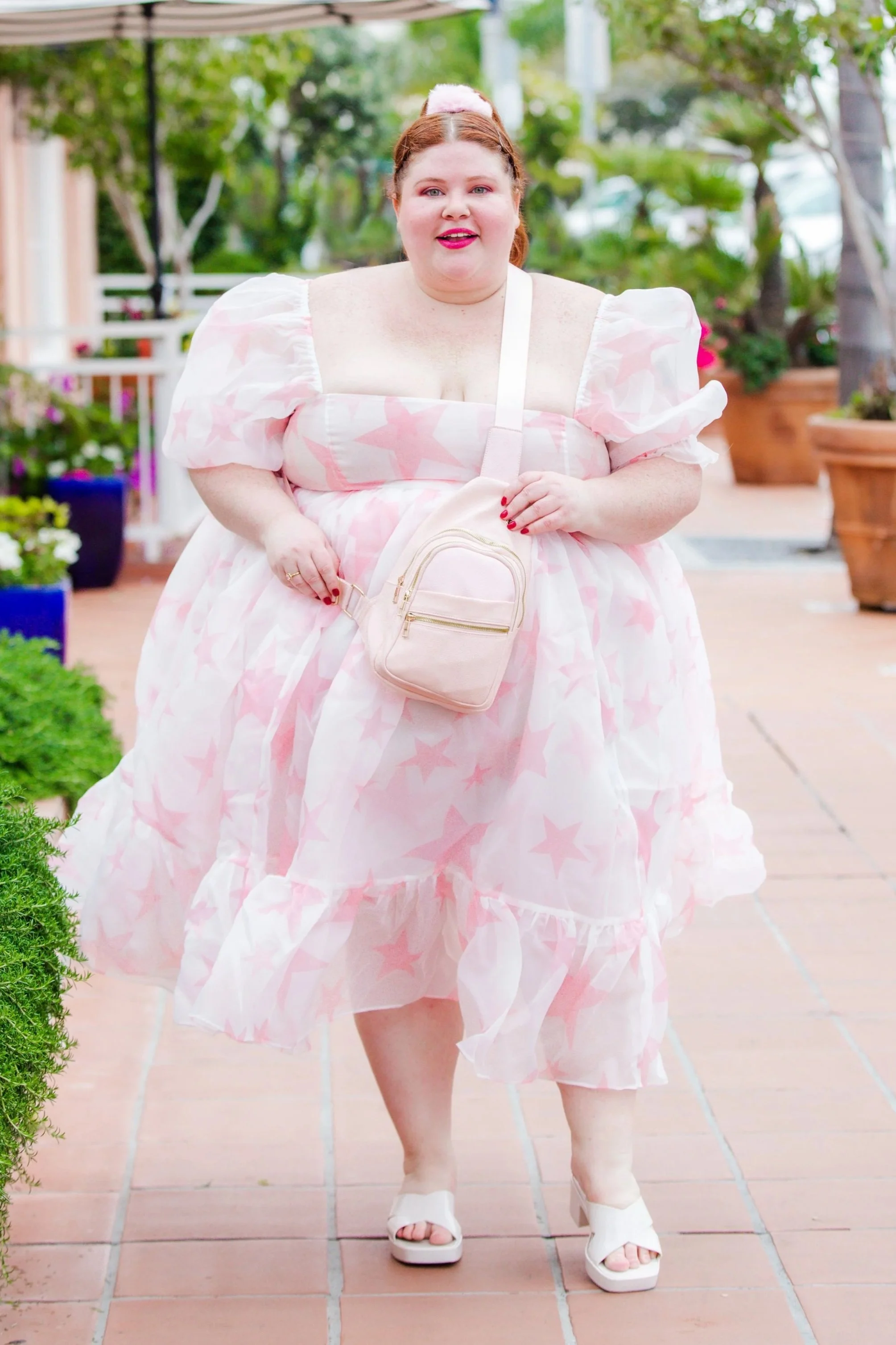 Plus size woman wearing a pink dress with a pink plus size crossbody bag.