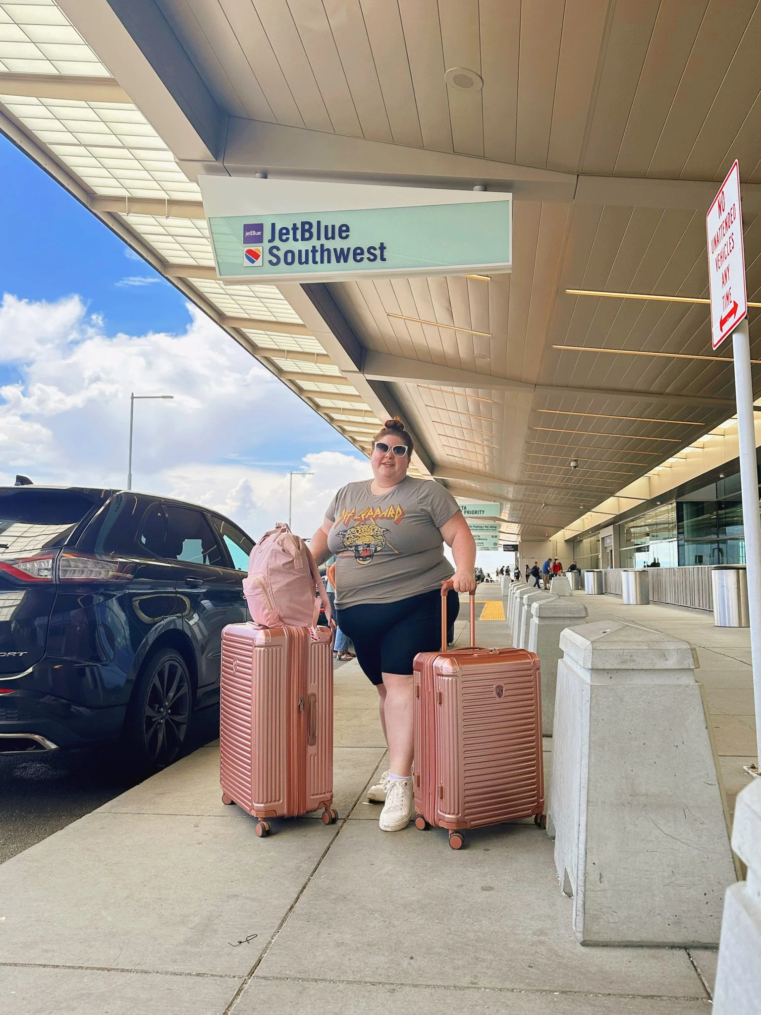 Plus size woman at the airport with pink luggage.
