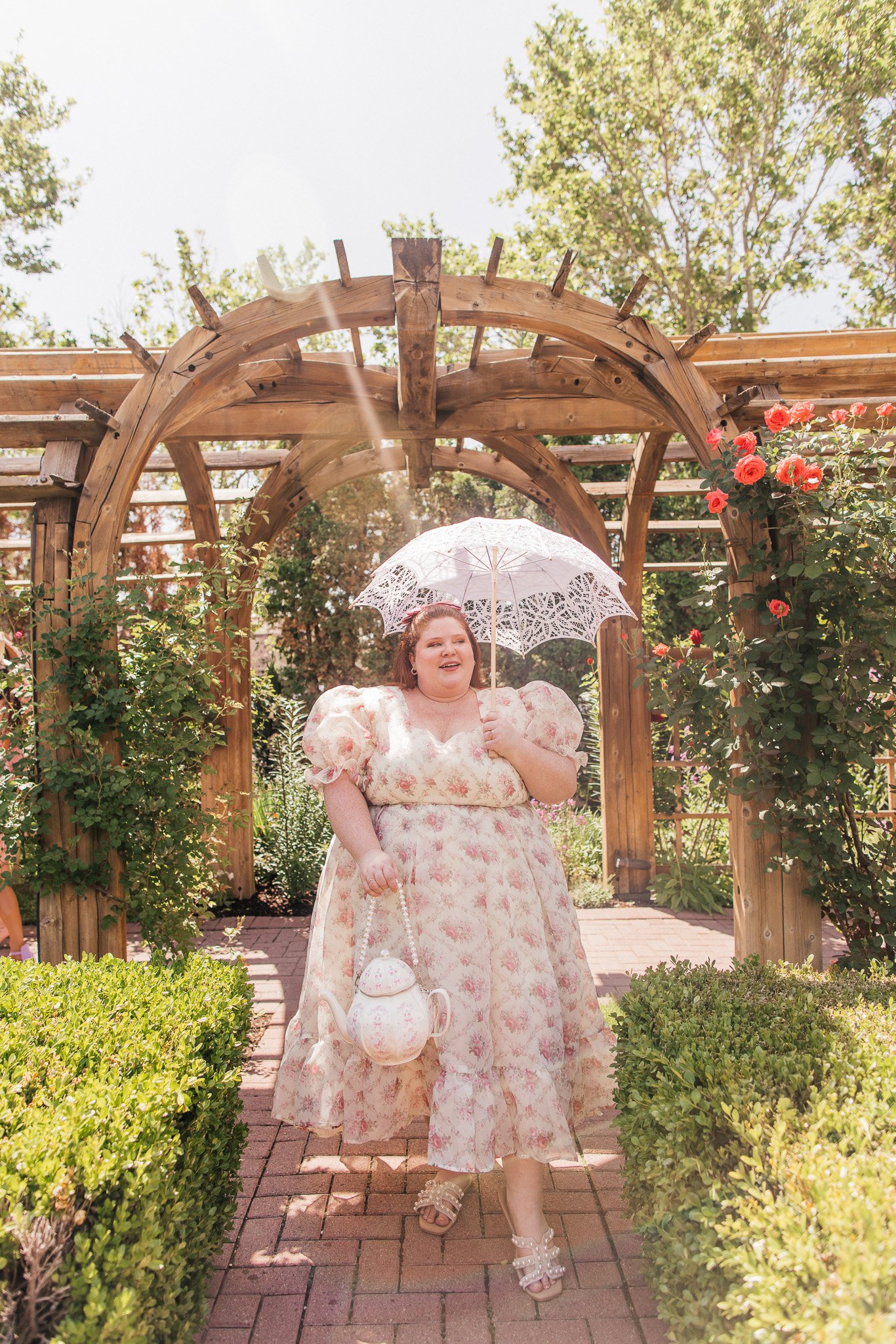 Plus size woman wearing a floral dress with lace umbrella in a garden