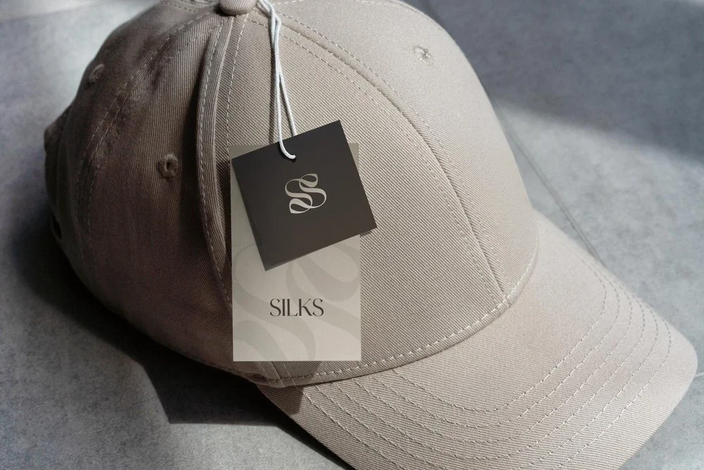 Geborduurd Silks logo op beige pet met label | Toegepaste merkidentiteit