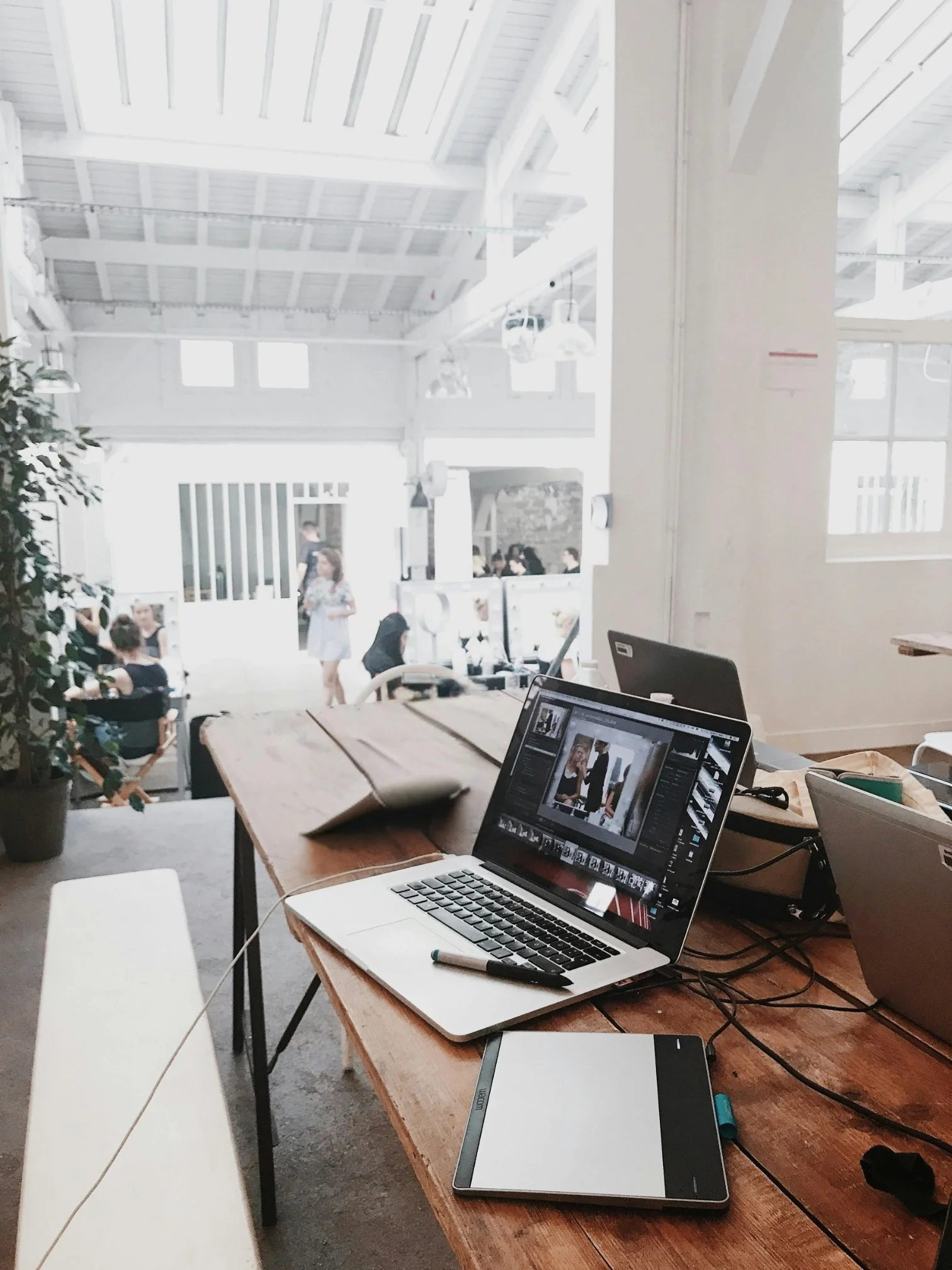 Team workspace with multiple laptops and creative tools — startup environment requiring commercial legal services from Pixel Legal