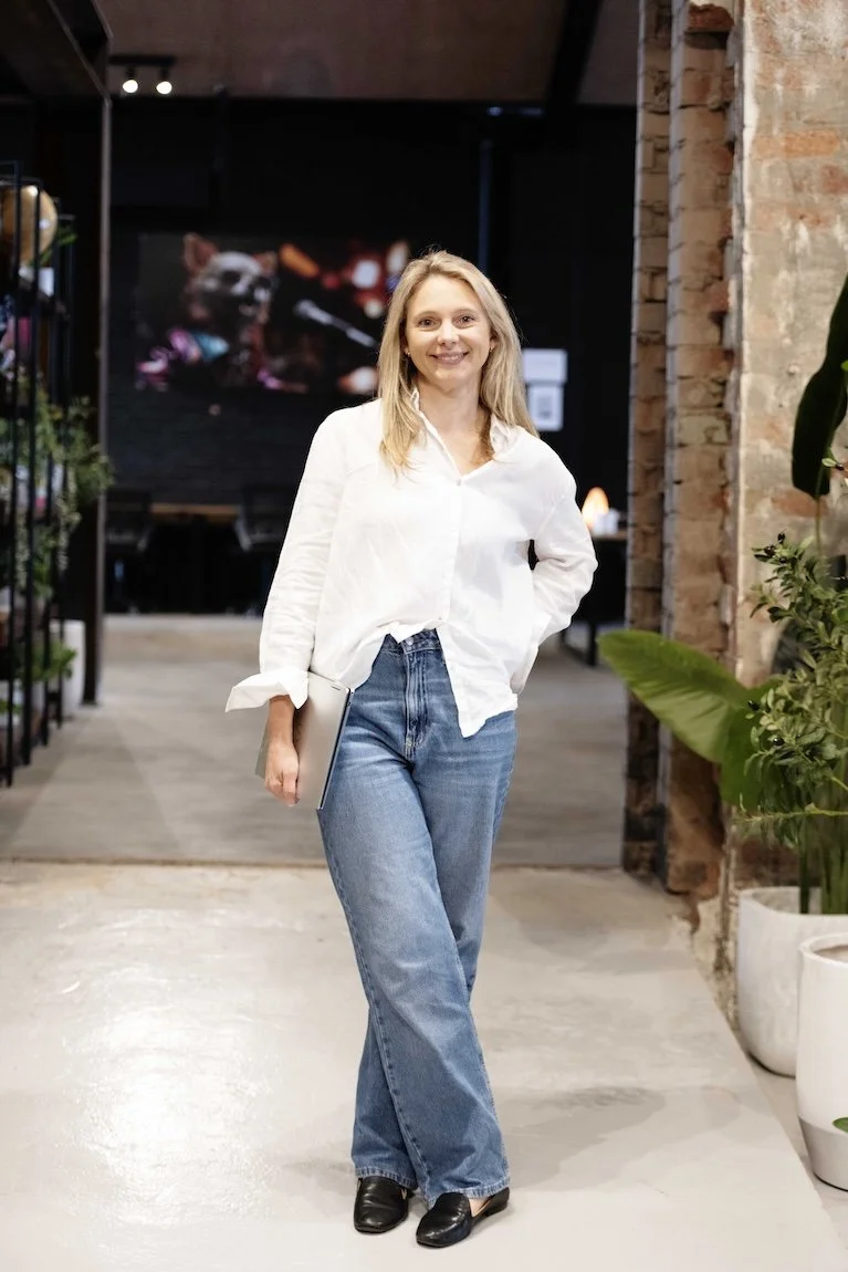 Calina Popovski, founder and lawyer holding laptop, smiling in modern office — ideal for legal support branding in FinTech and EdTech.