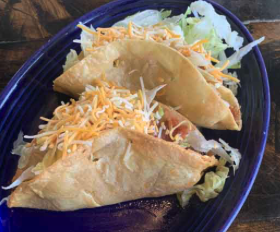Plate of three fried wontons with shredded cheese, lettuce, and shredded cheese