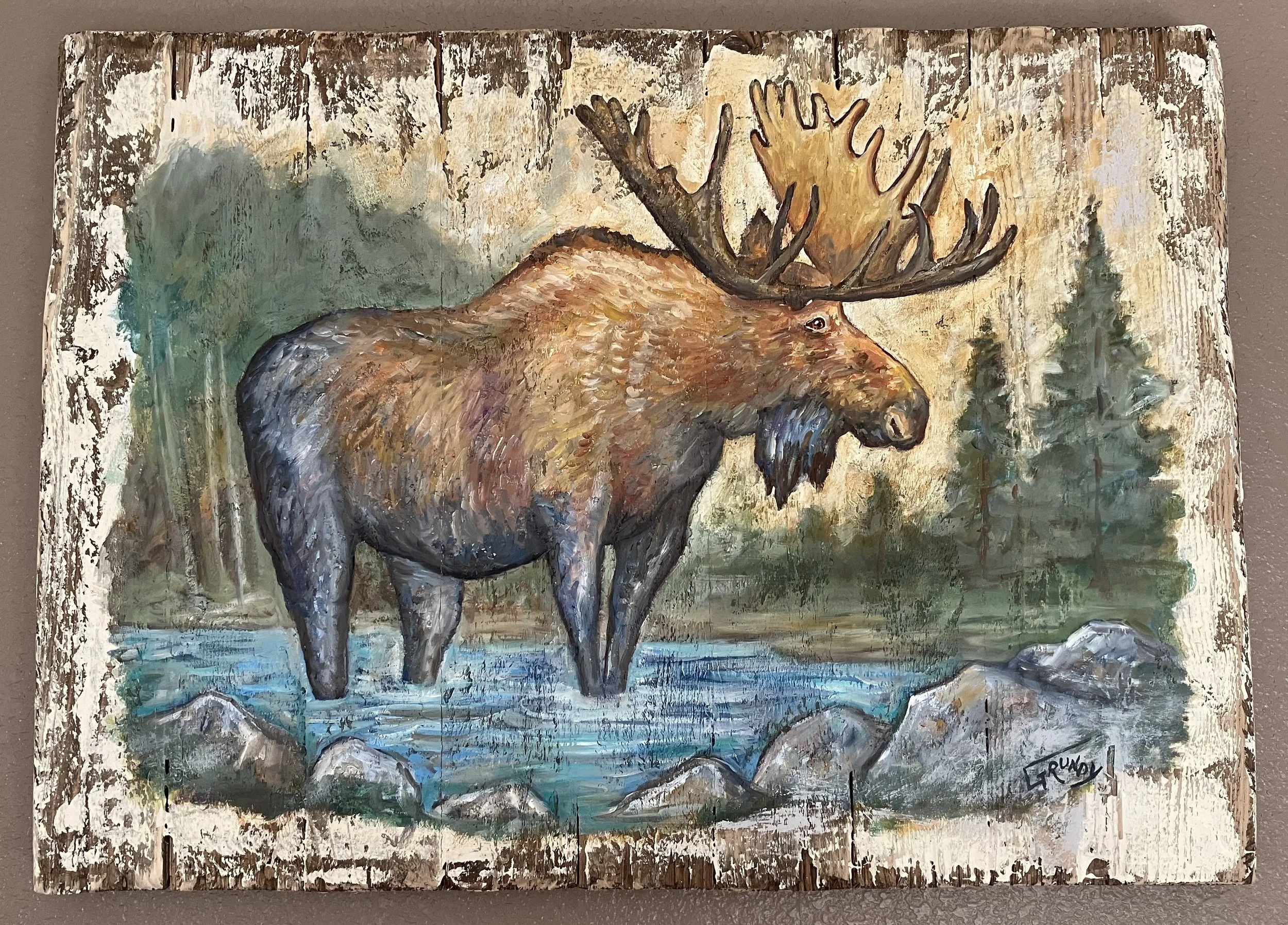 Painting of a moose standing in a river with rocks, surrounded by trees and a forest background.