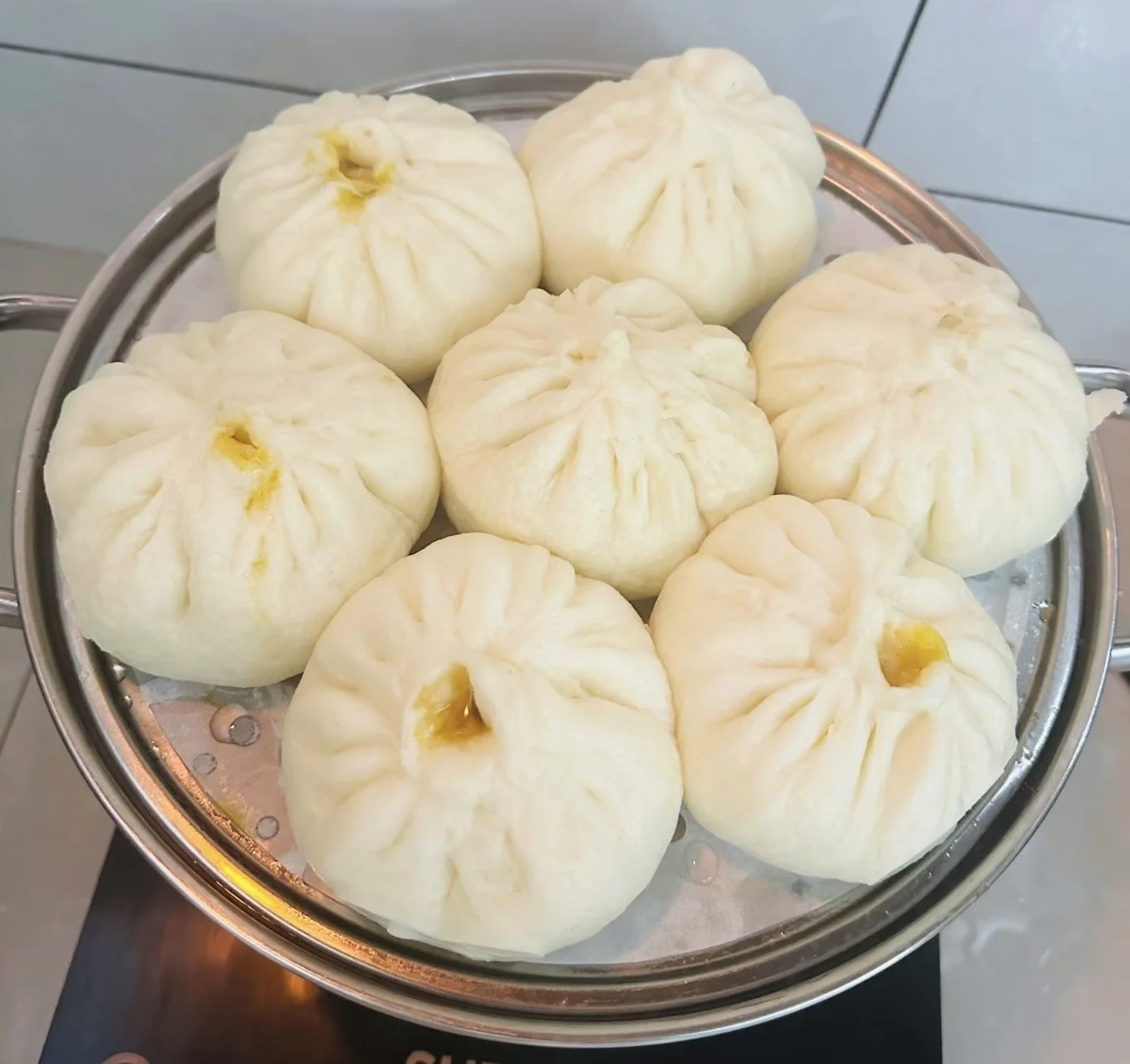 Nine steamed buns on a metal tray.
