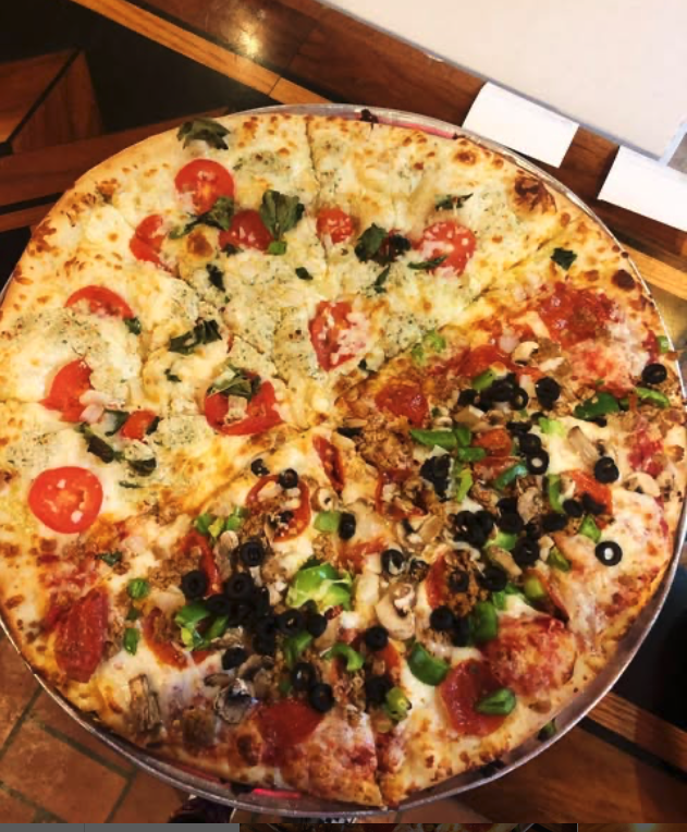 Large pizza with half topped with tomato slices, basil, and cheese; other half with pepperoni, black olives, mushrooms, green onions, and crumbled sausage.
