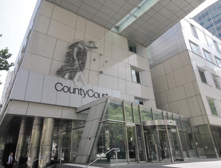 Exterior view of a modern courthouse building with a sculpture of a woman holding scales, and the word 'CountyCourt' on the facade.