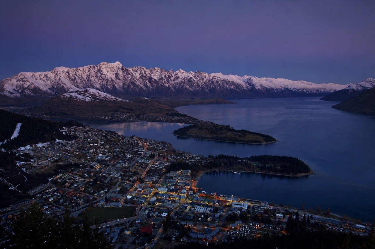Aerial view of modern black houses on a hillside overlooking a Queenstown lake.