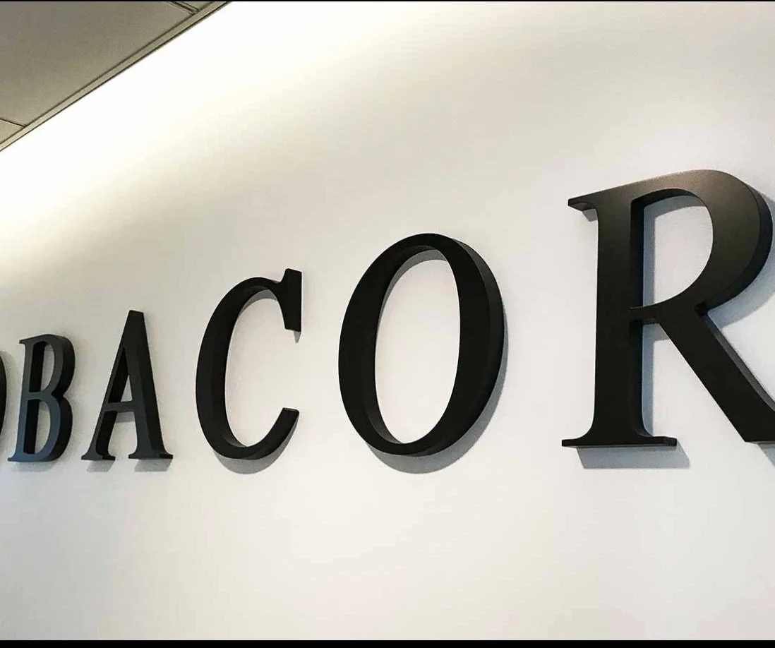 Black acrylic dimensional letters pin mounted flushed on white wall.