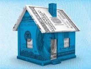 A small house model made from folded US dollar bills with a blue building block on top, set against a light blue background.