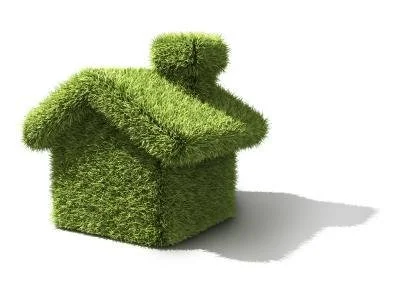 House-shaped object covered in green grass or turf, casting a shadow.