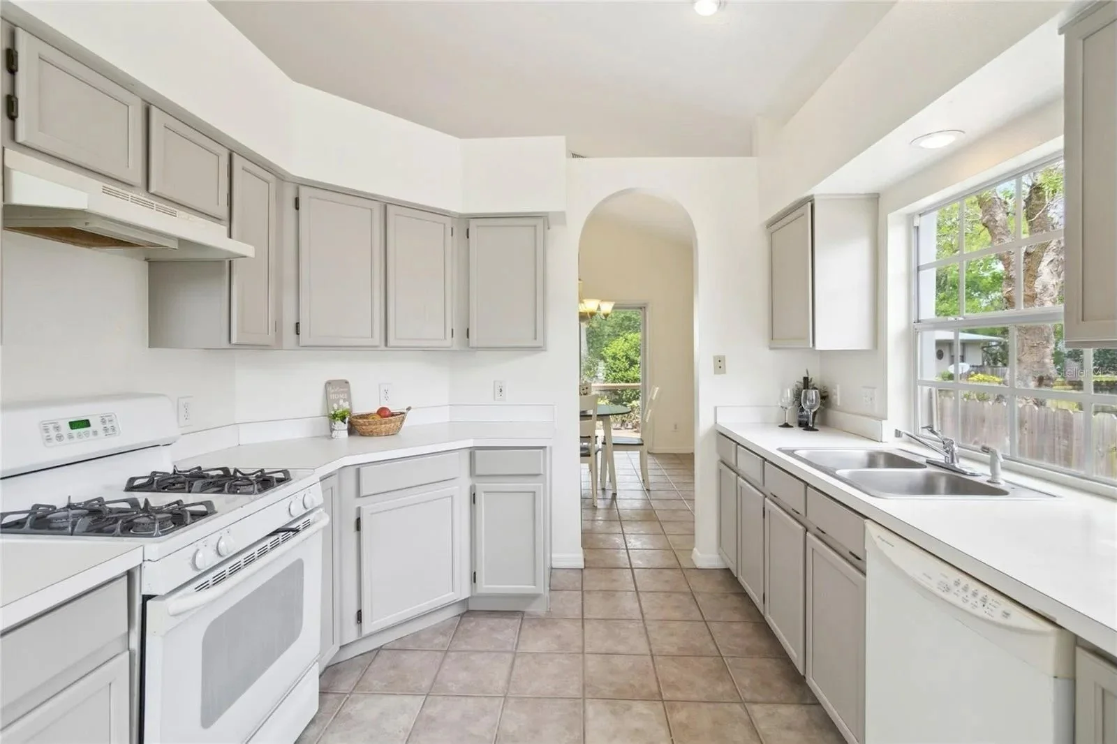 A cartoon woman with brown hair, glasses, and earrings, wearing a white button-up shirt and pink pants, smiling with hands in pockets.