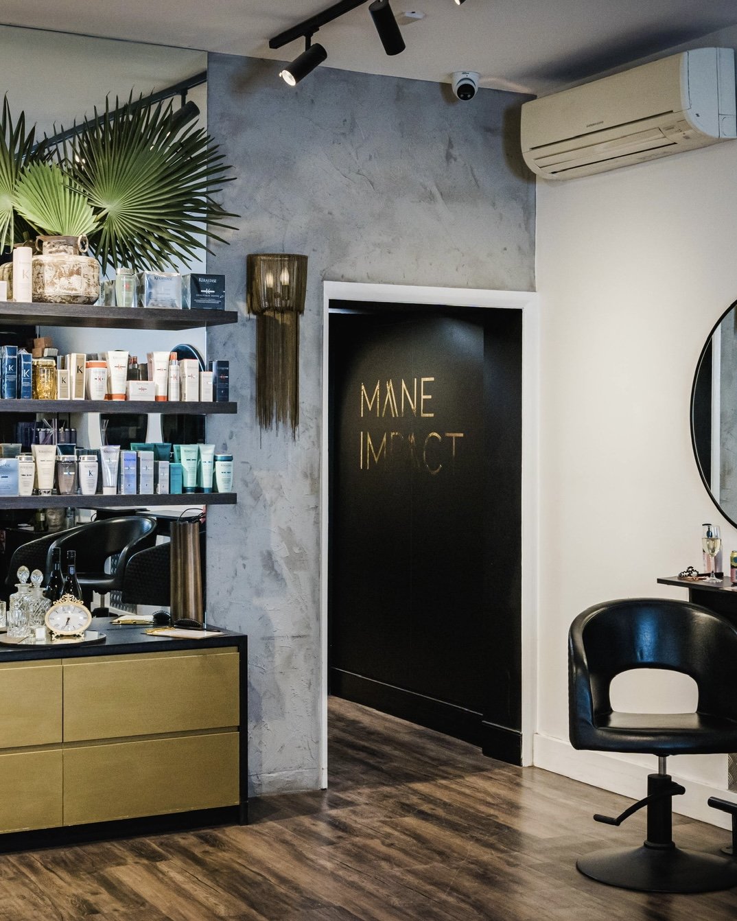 Inside Mane Impact, a luxury hair salon in Fairlight, NSW, with a black styling chair, timber floors, and a Kérastase product display.