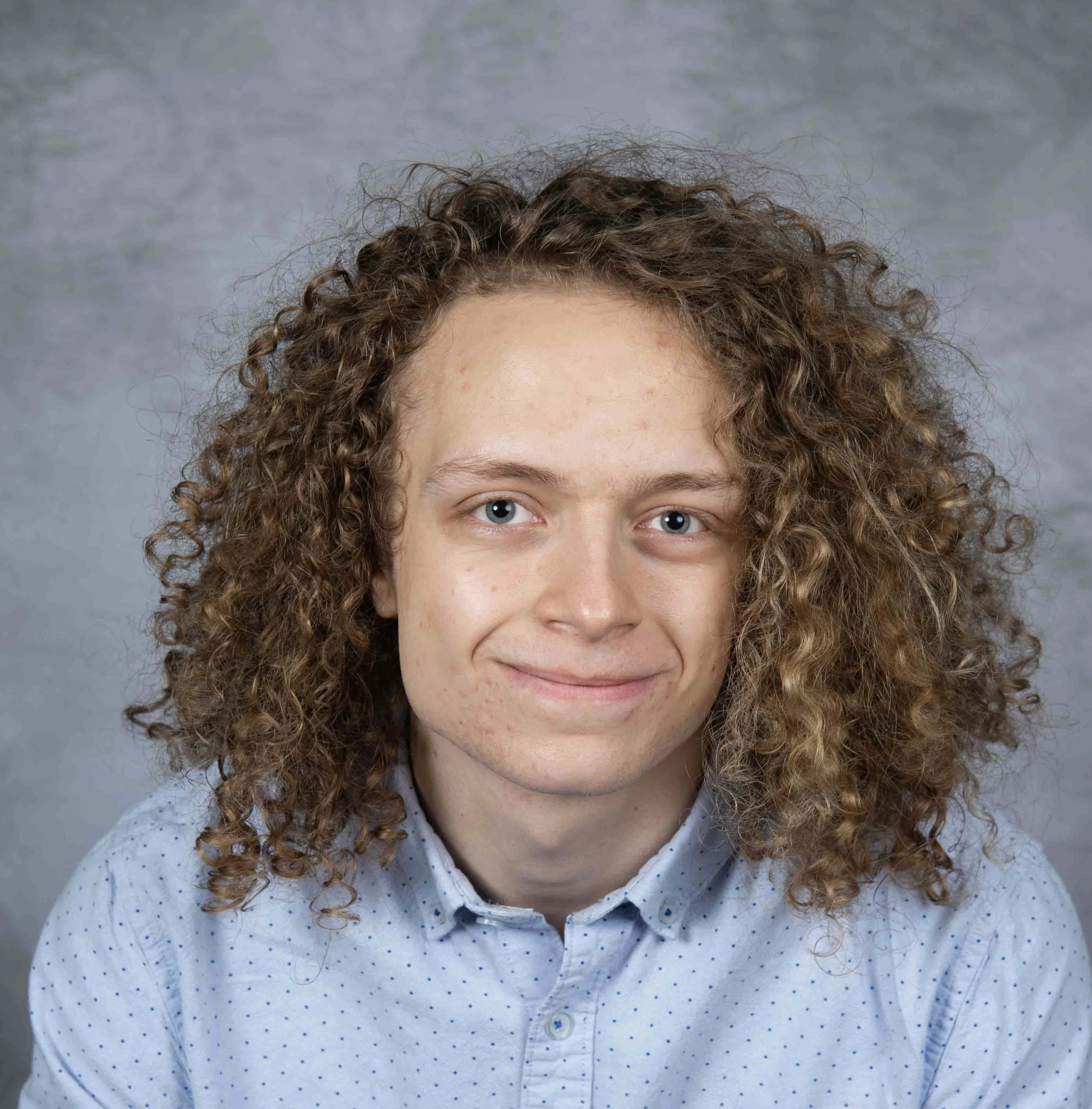 Close up portrait of young man with long curly hair.