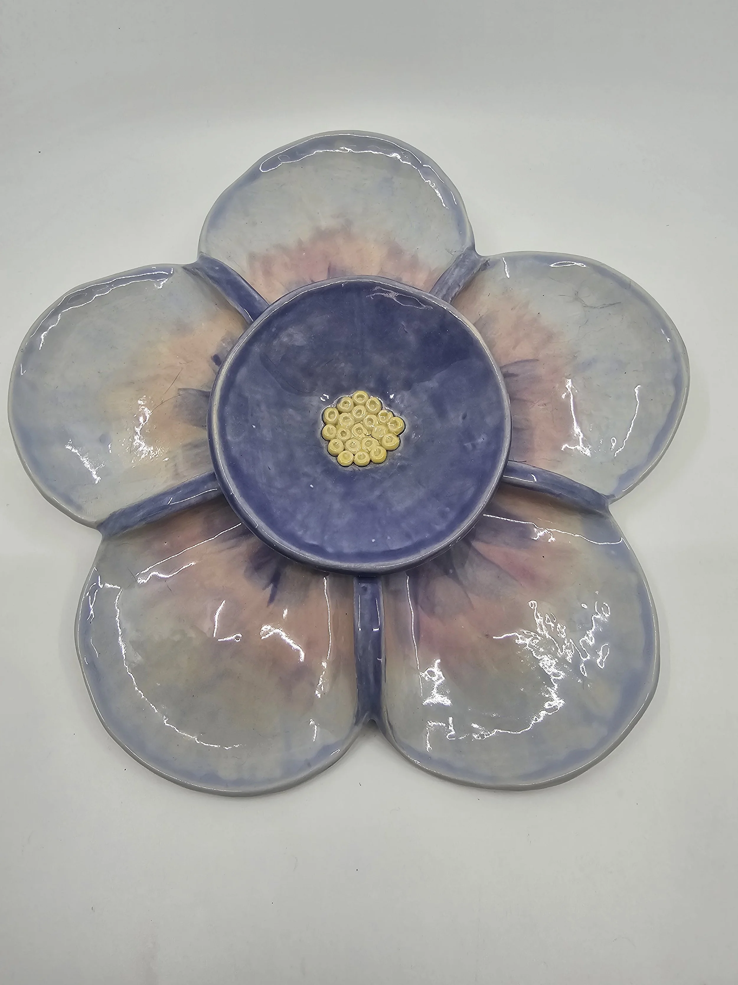 Ceramic dish shaped like a flower with six petals and a central bowl, painted in pastel shades of blue, pink, and cream, with small yellow beads inside the central bowl.