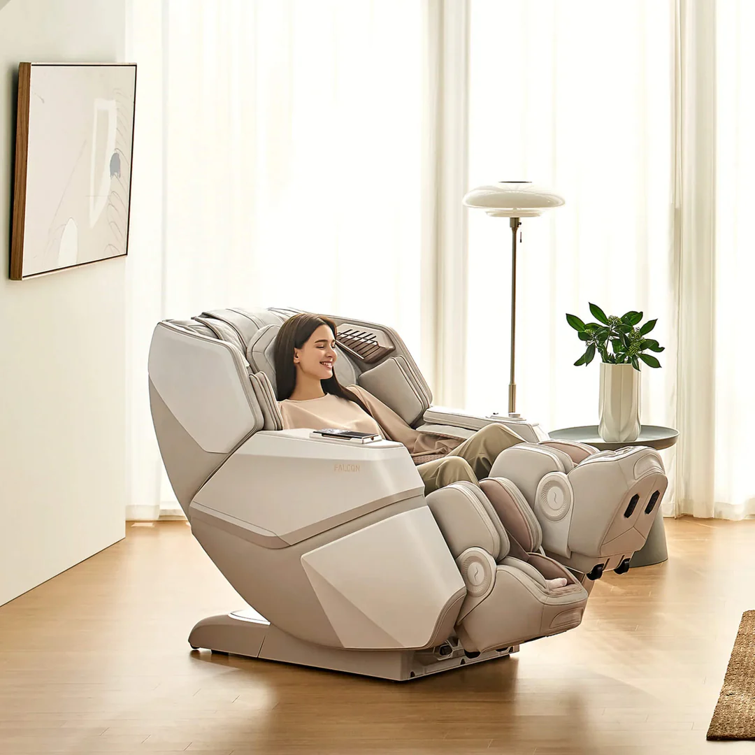 A woman relaxing in a beige massage chair in a bright living room with white curtains, a potted plant, and a tall floor lamp.