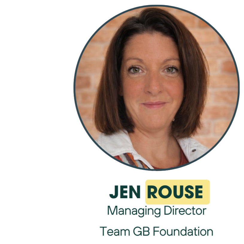 Headshot of a woman with medium-length brown hair and green eyes, smiling slightly, against a brick wall background.