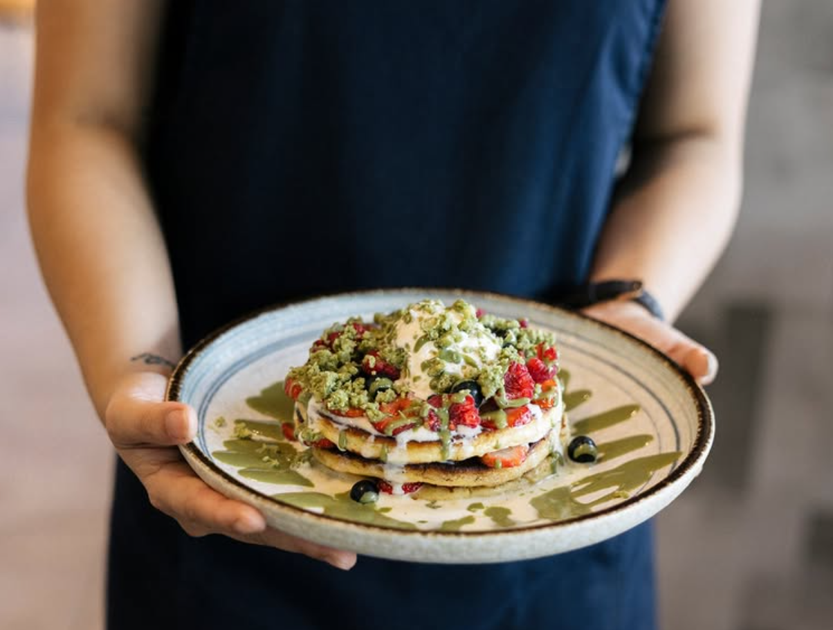 Oyku Pistachio Cream Sauce drizzled over pancakes with cream, berries and crumble at Leaf Café — gourmet pistachio dessert in Australia
