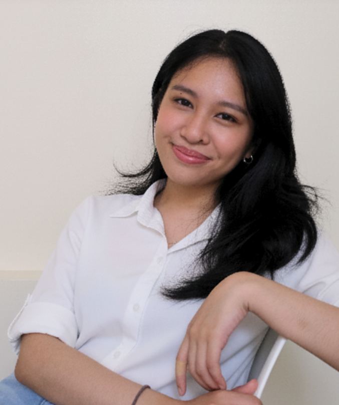 a woman sitting down on a chair with her arm placed on the back of the chair