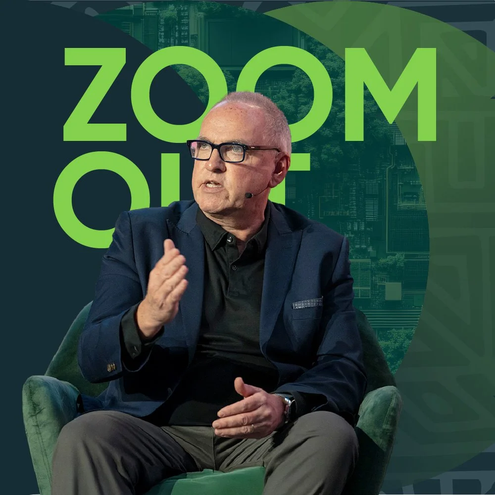 Our founder Kevin Dunckley with a ZOOM OUT background, sitting on a comfortable chair at a presentation with audience.