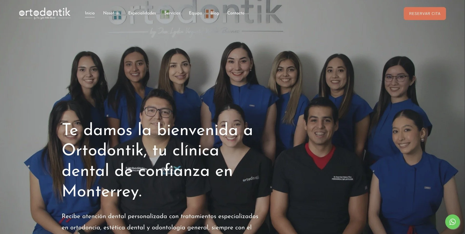 Grupo de profesionales en odontología en una clínica dental llamada Ordotontik, con fondo gris y logotipo visible, todos vestidos con uniformes azules y negros, sonriendo para la foto.