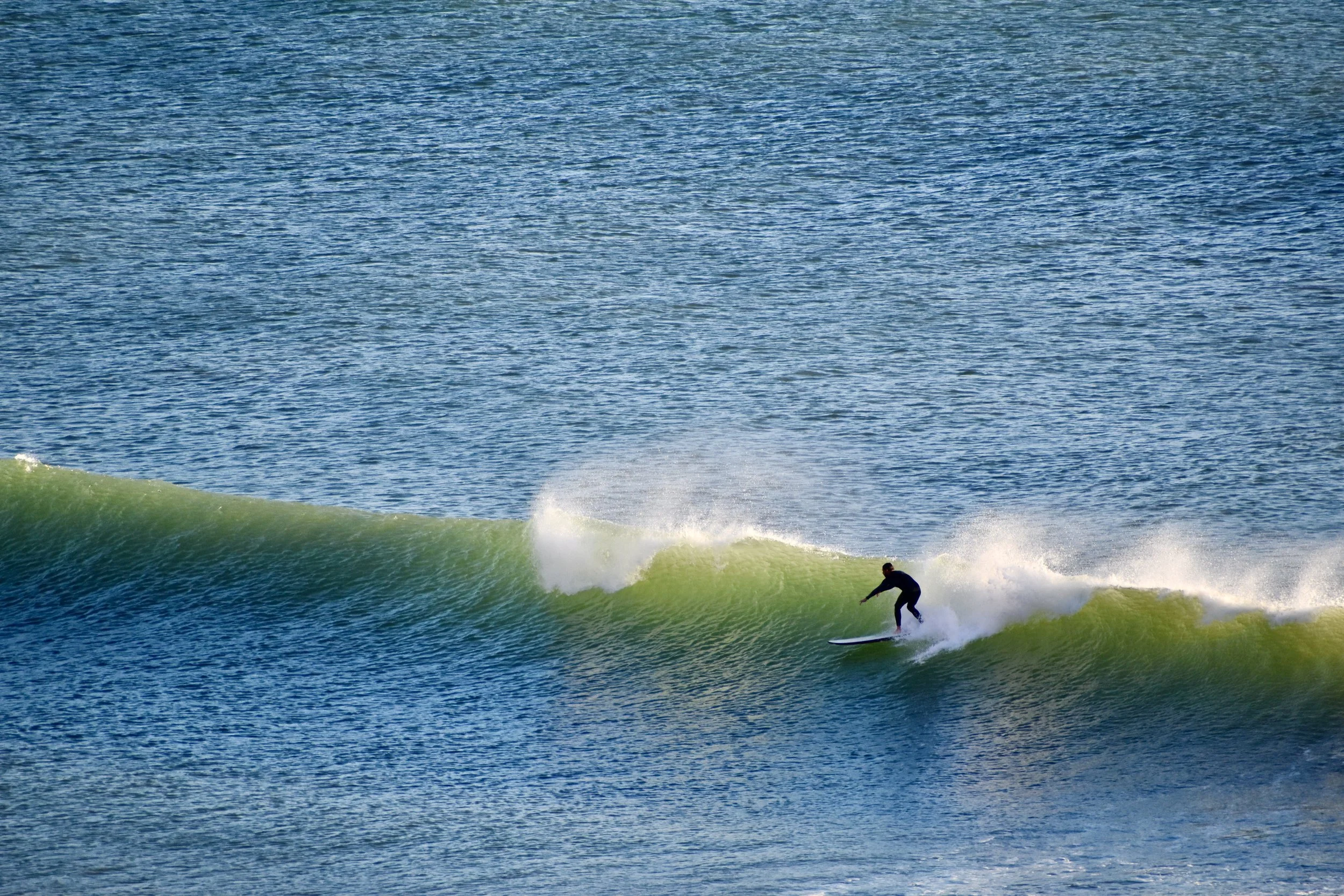A person surfing on a green wave in the ocean.