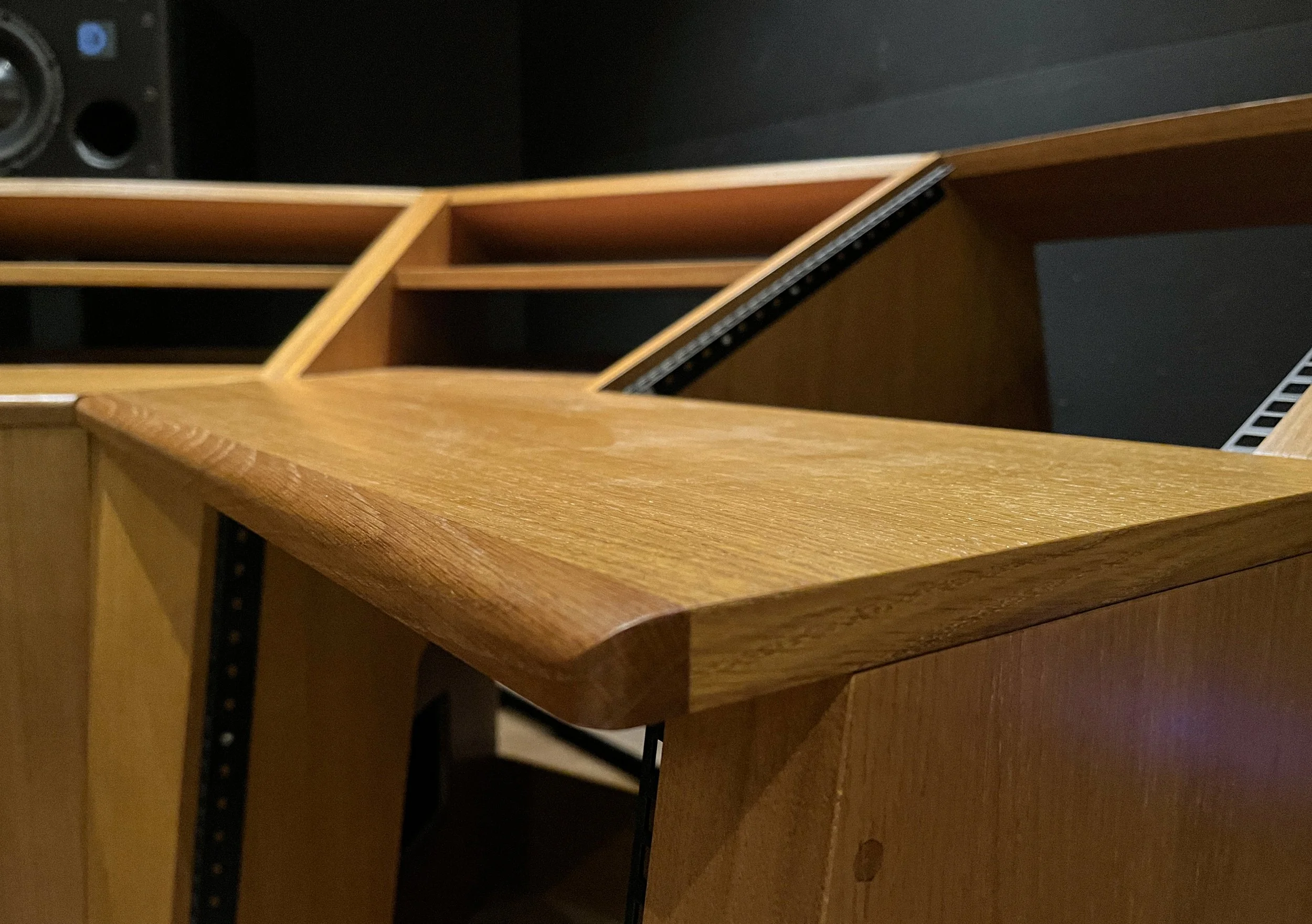 Une pièce avec un meuble en bois avec plusieurs compartiments ouverts, un plateau en bois arrondi et une étagère métallique visible en arrière-plan.