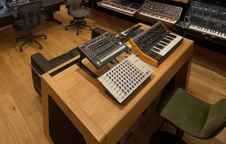 Un studio de musique avec diverses claviers et synthétiseurs sur une table en bois.