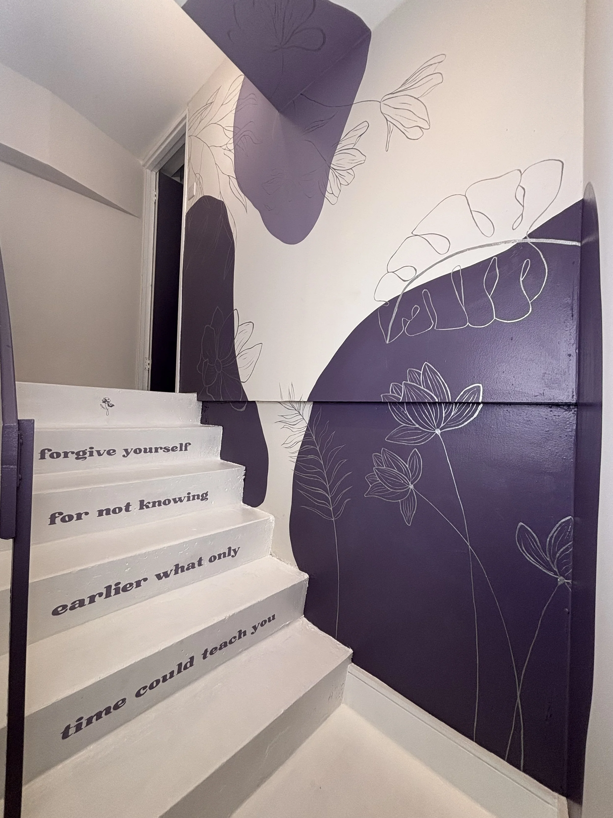 hand painted botanical mural in pilates and yoga studio featuring calming floral line art, abstract shapes and inspirational stair typography. herts mural artist