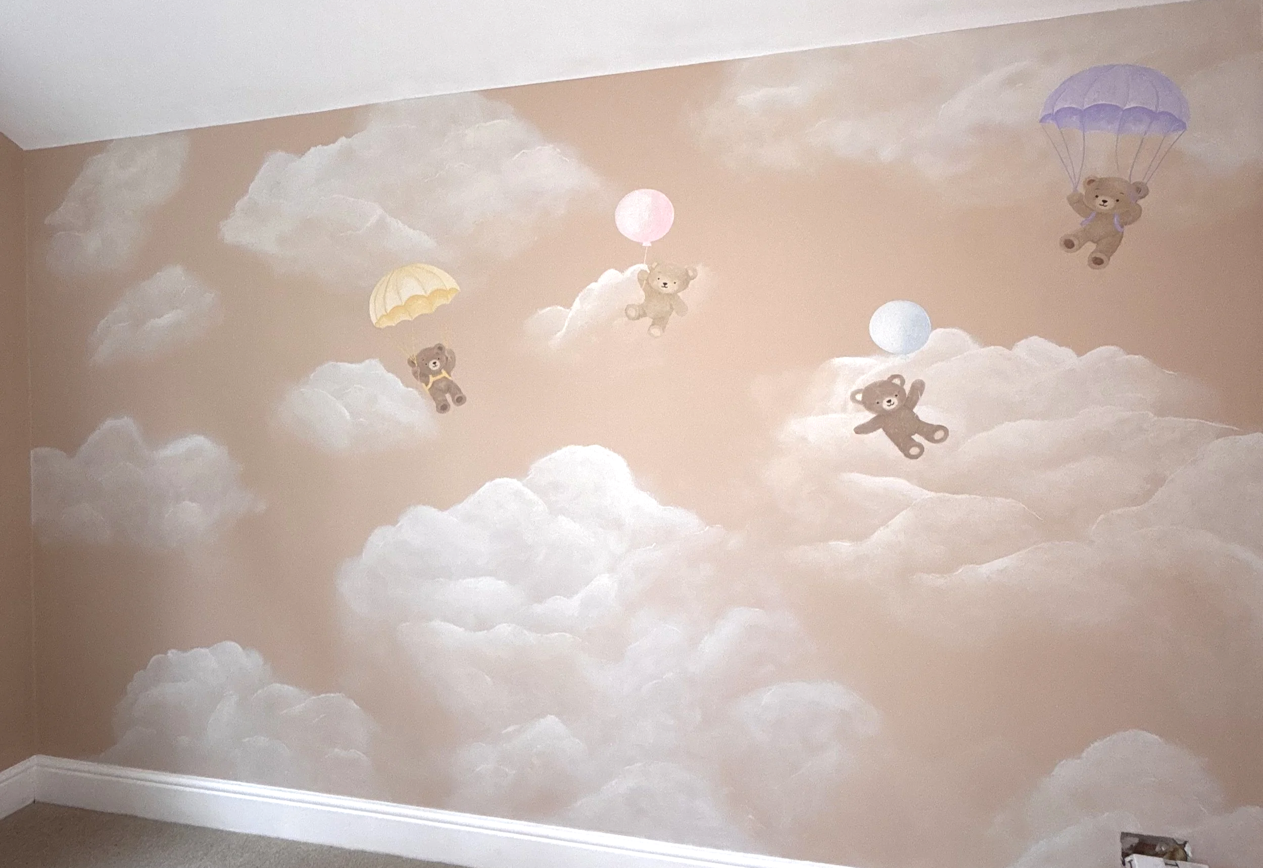 charming hand painted mural of bears floating among the clouds with a balloon and parachute, creating a playful whimsical nursery room. perfect for play cafes, family rooms and baby rooms alike. Hertfordshire based muralist and artist