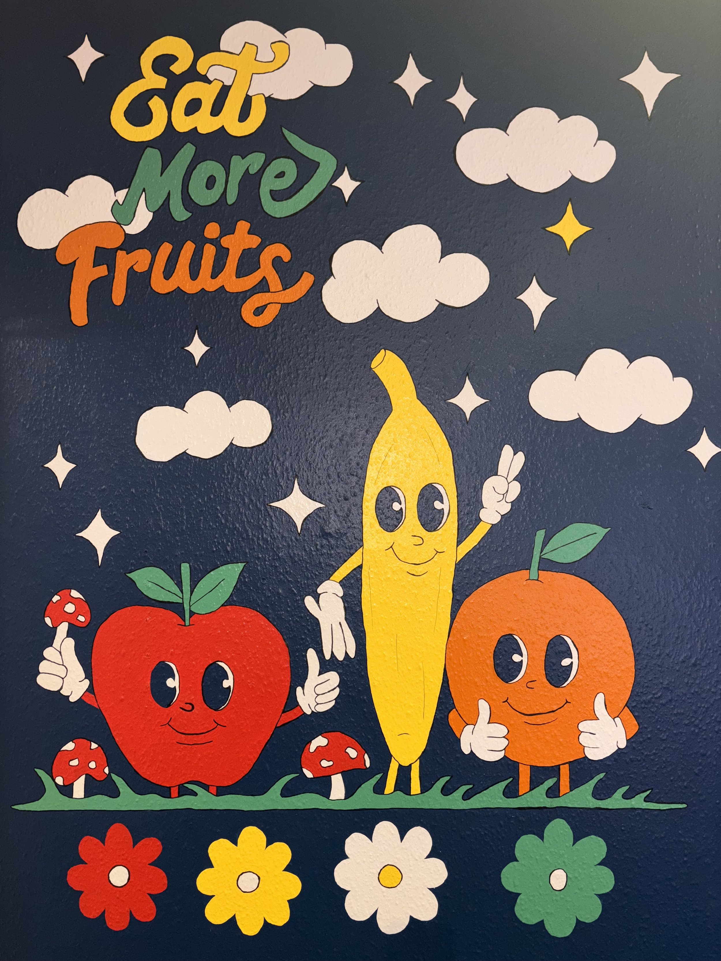Hand-painted “Eat More Fruit” mural by Mack in Colour featuring colourful fruit illustrations in a bright, playful style. uk based artist. mural artist uk. banana art, apple wall art, orange b