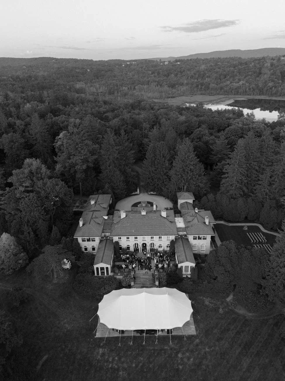 Aerial view of a large mansion with a crowd gathered outside.
