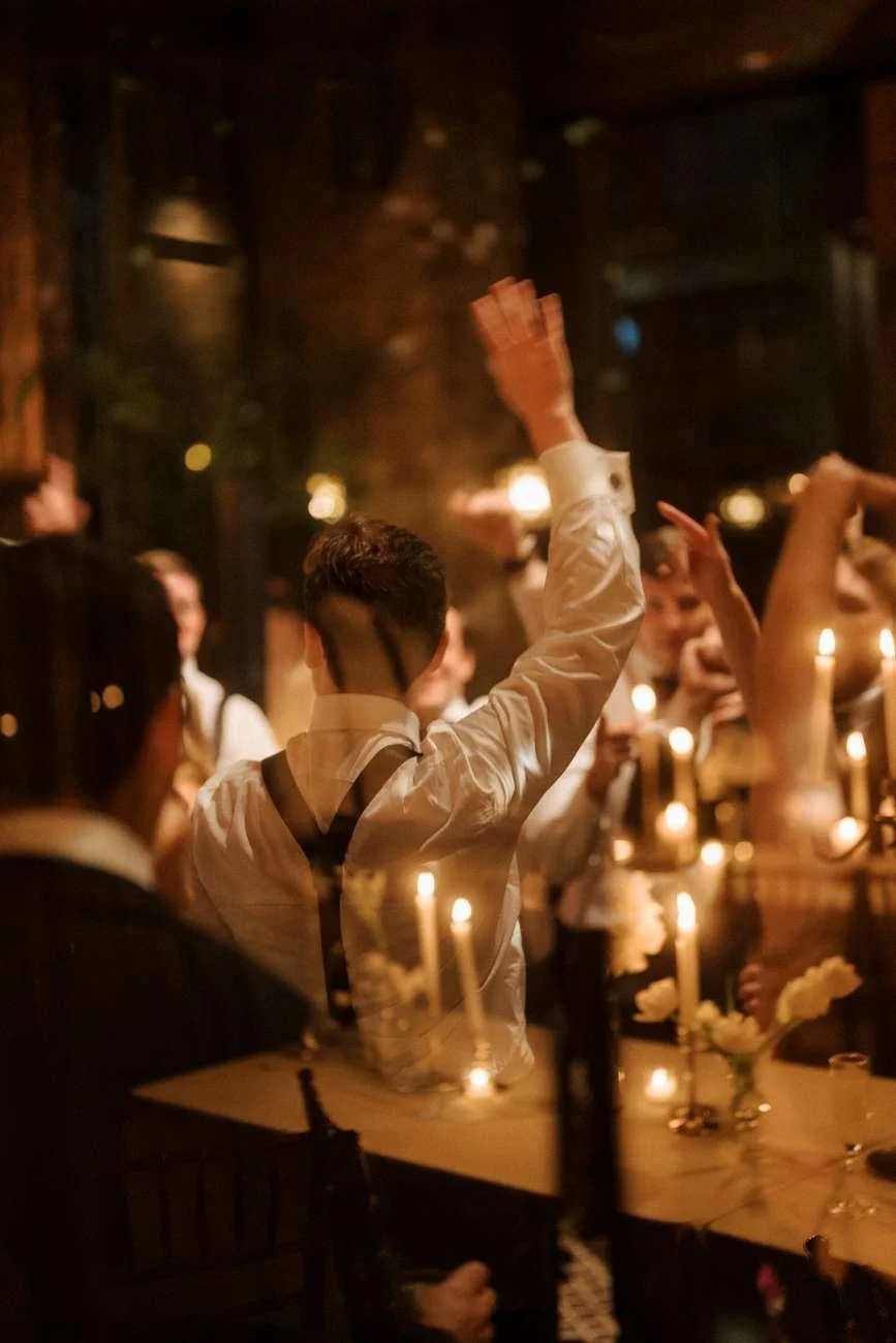 People gathered at a dimly lit celebration or banquet, with candles on the table.