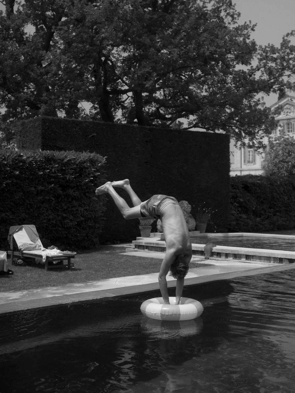 A person doing a handstand on a life preserver floating in a swimming pool.