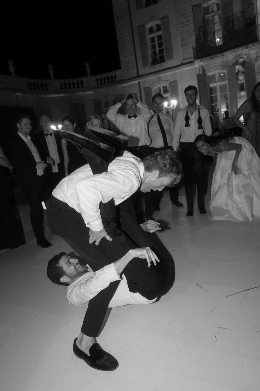 Couple performing an acrobatic dance routine at a formal event, on a large outdoor patio at night.