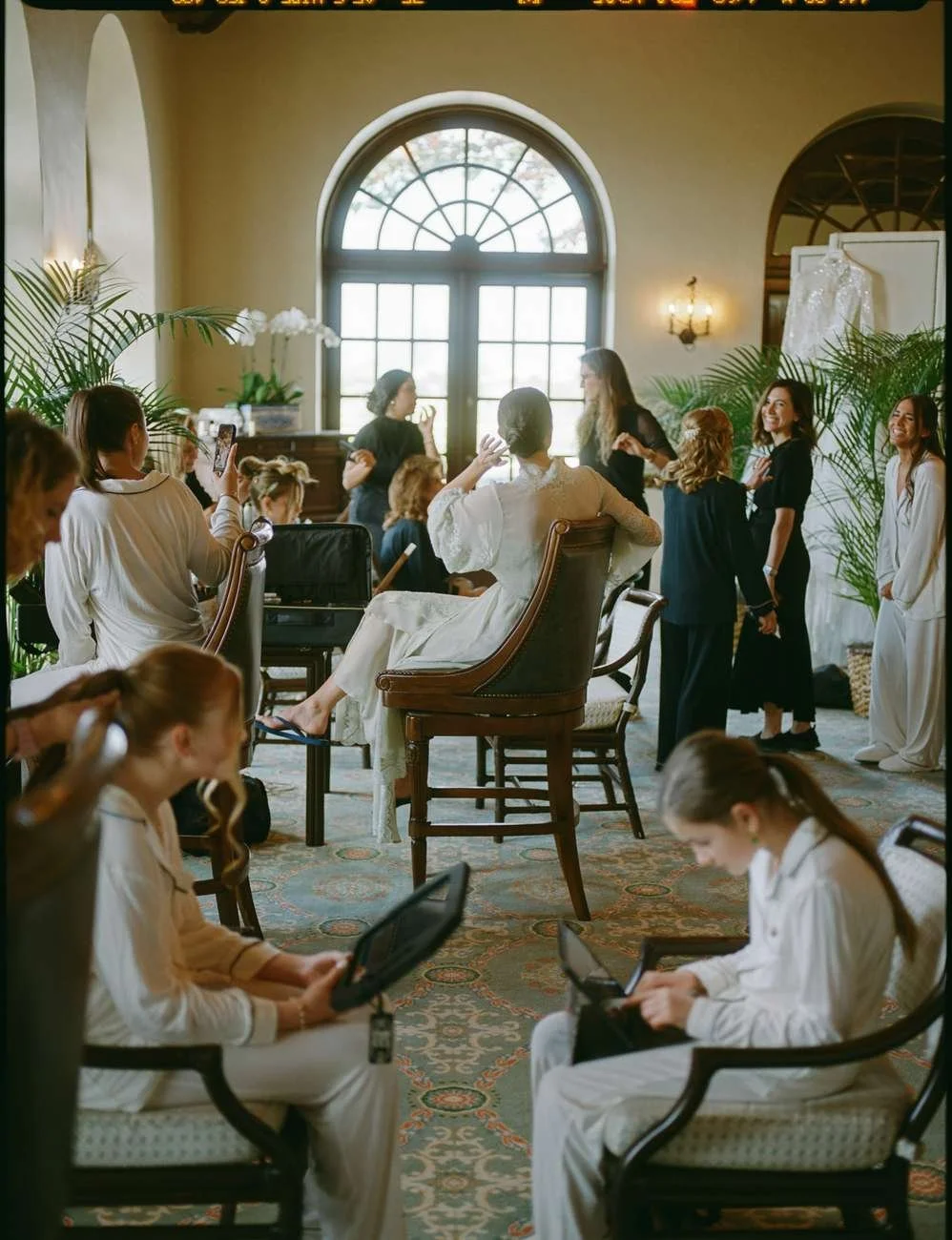 Women preparing for a wedding, with some seated and others standing.