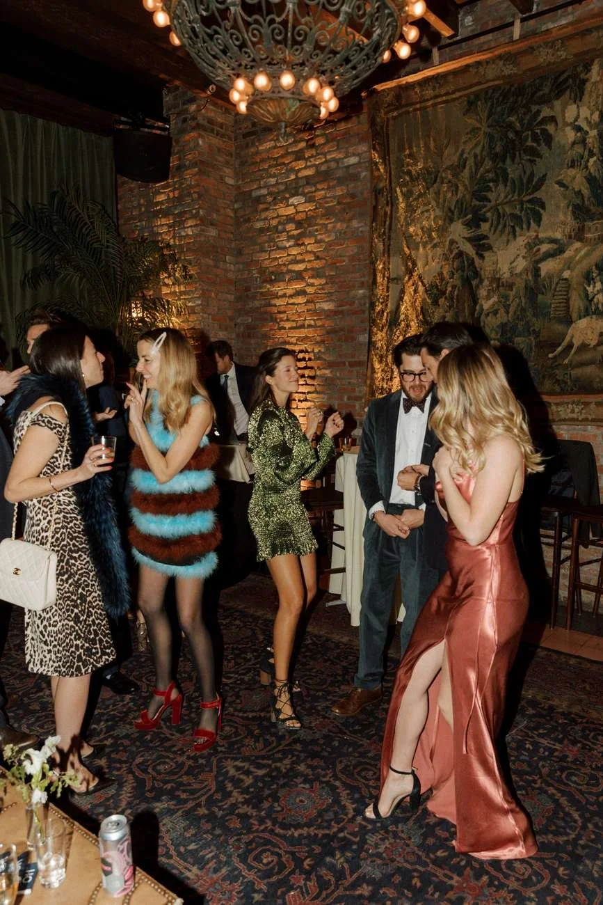 A group of people dressed in formal and fashionable attire enjoying a social event in a stylish venue.