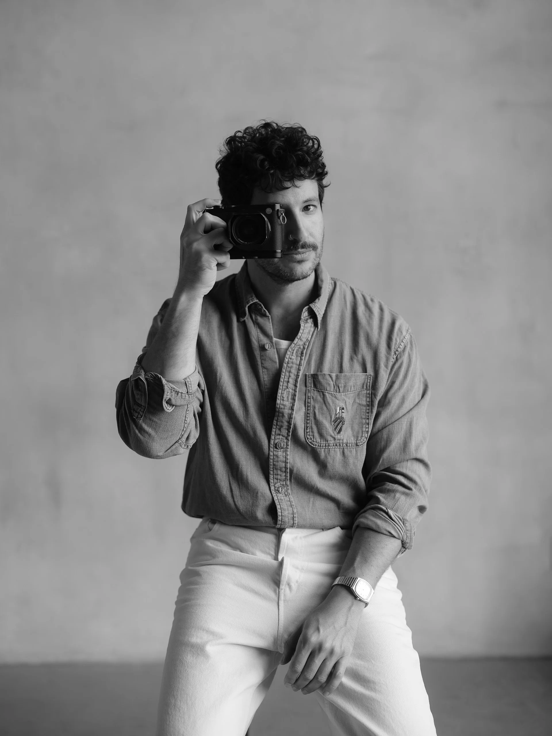 Black and white photo of a man taking a picture with a camera.