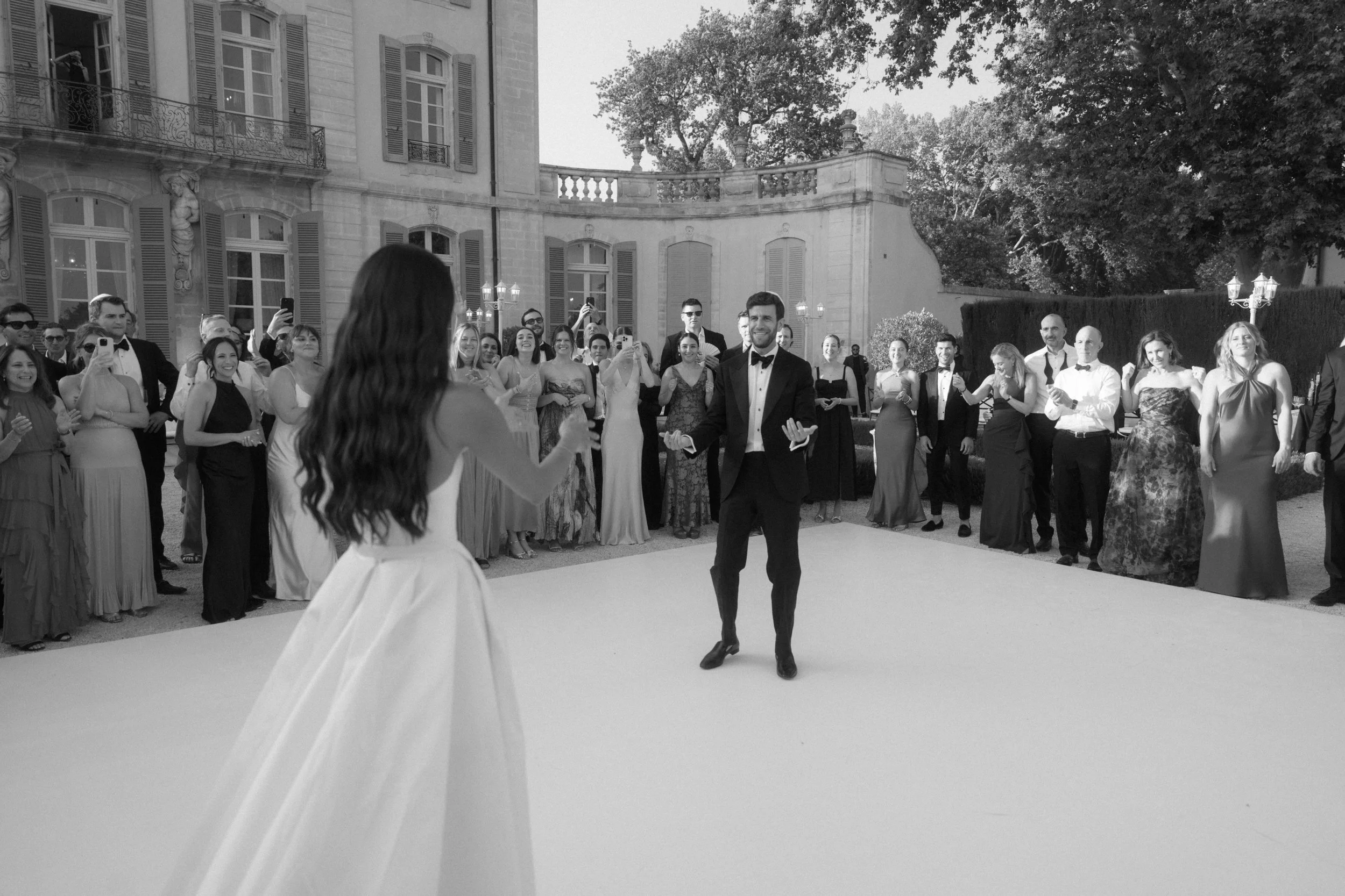 A wedding dance with the bride and groom in the center, surrounding by friends and family.