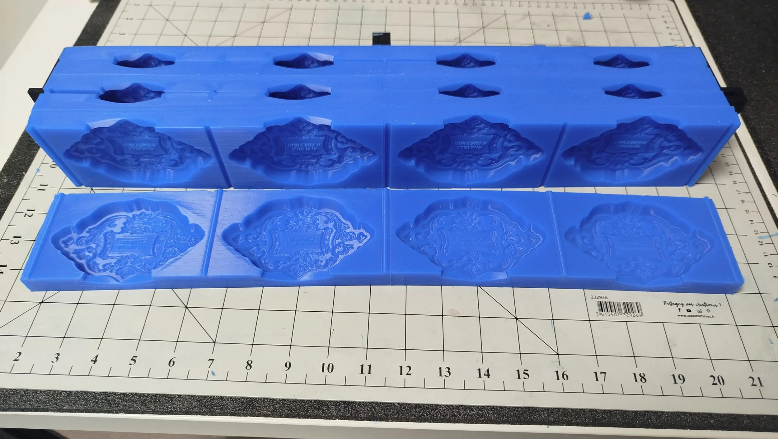 Un moule en silicone bleu contenant des motifs décoratifs, placé sur une surface avec un tapis de découpe.