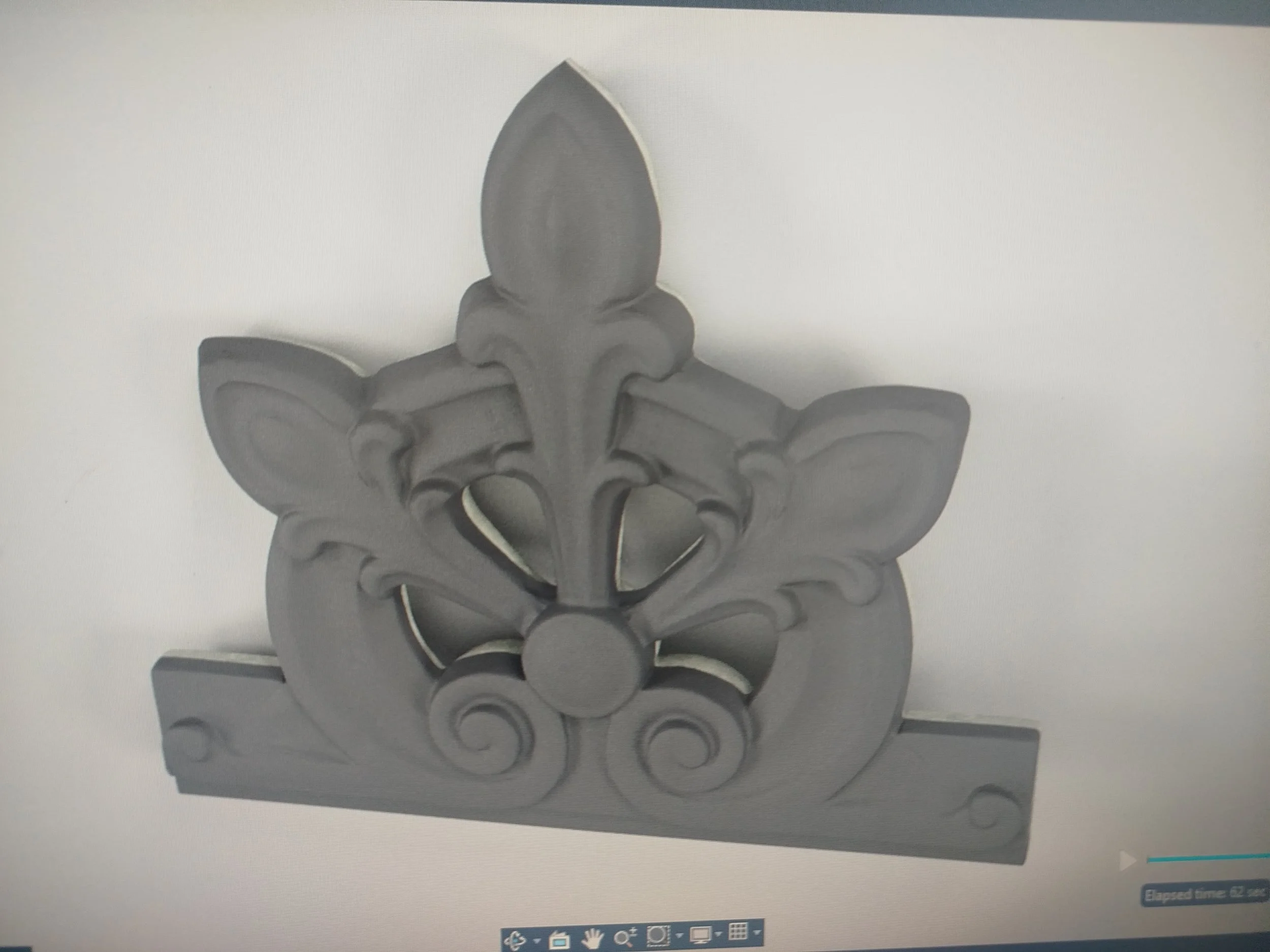 Décoratif en forme de fleur ou de feuille en relief, probablement en métal ou en bois, de couleur gris foncé.