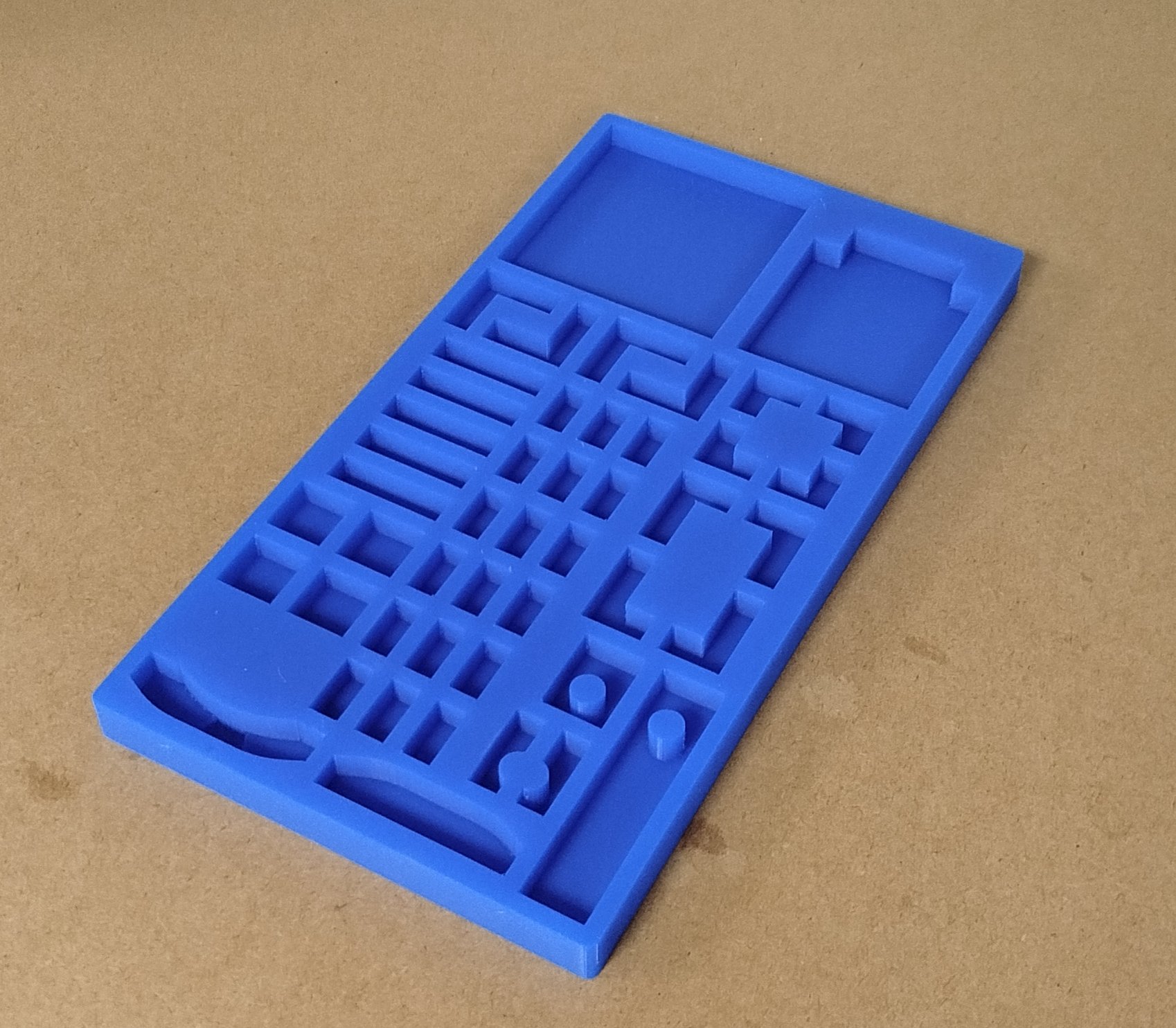 Plaque de test pour circuits imprimés, en plastique bleu avec plusieurs compartiments et rangées de petites sections pour placement de composants.