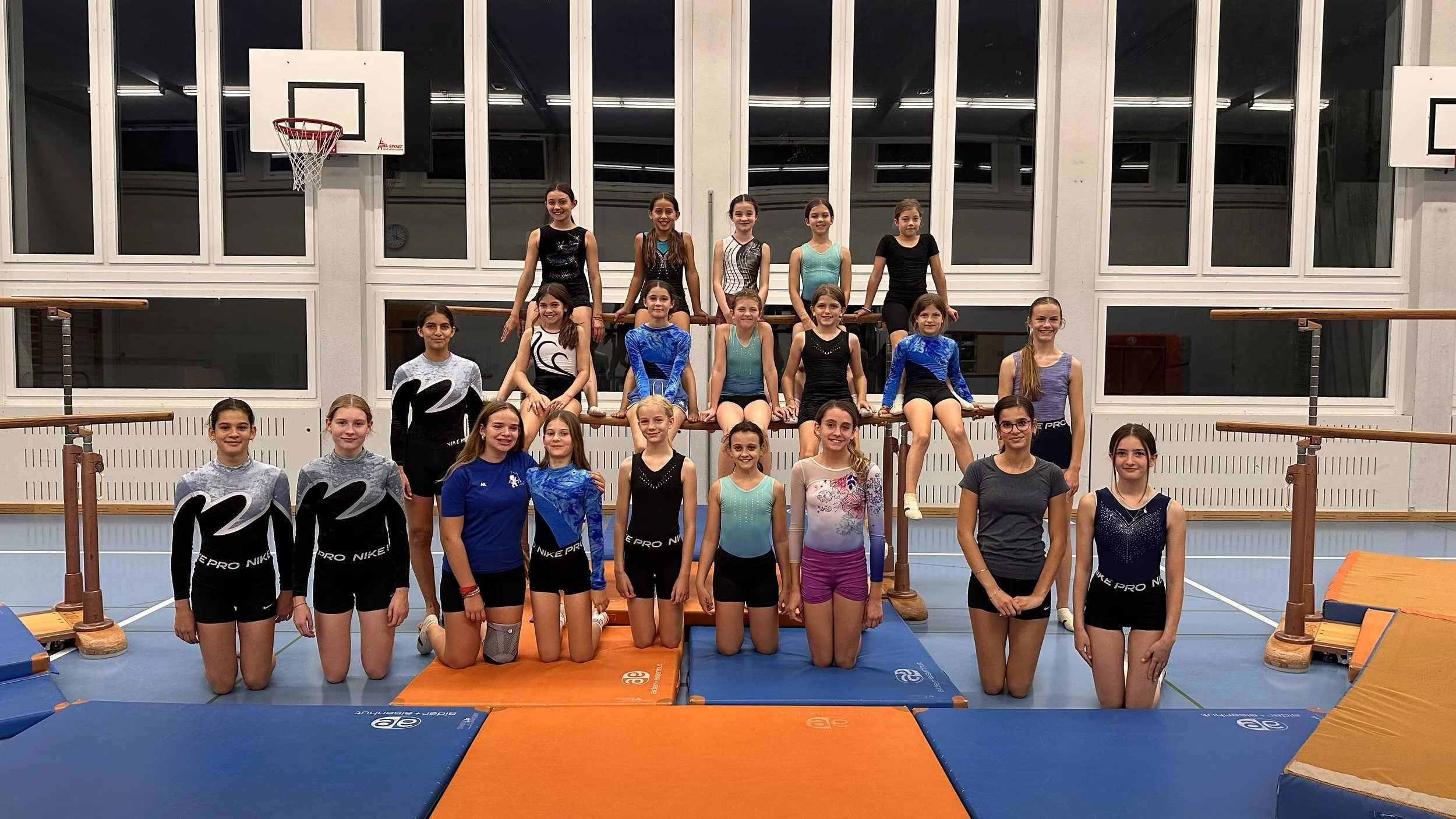 Gruppe von jungen Turnerinnen beim Geräteturnentraining in einer Turnhalle.
