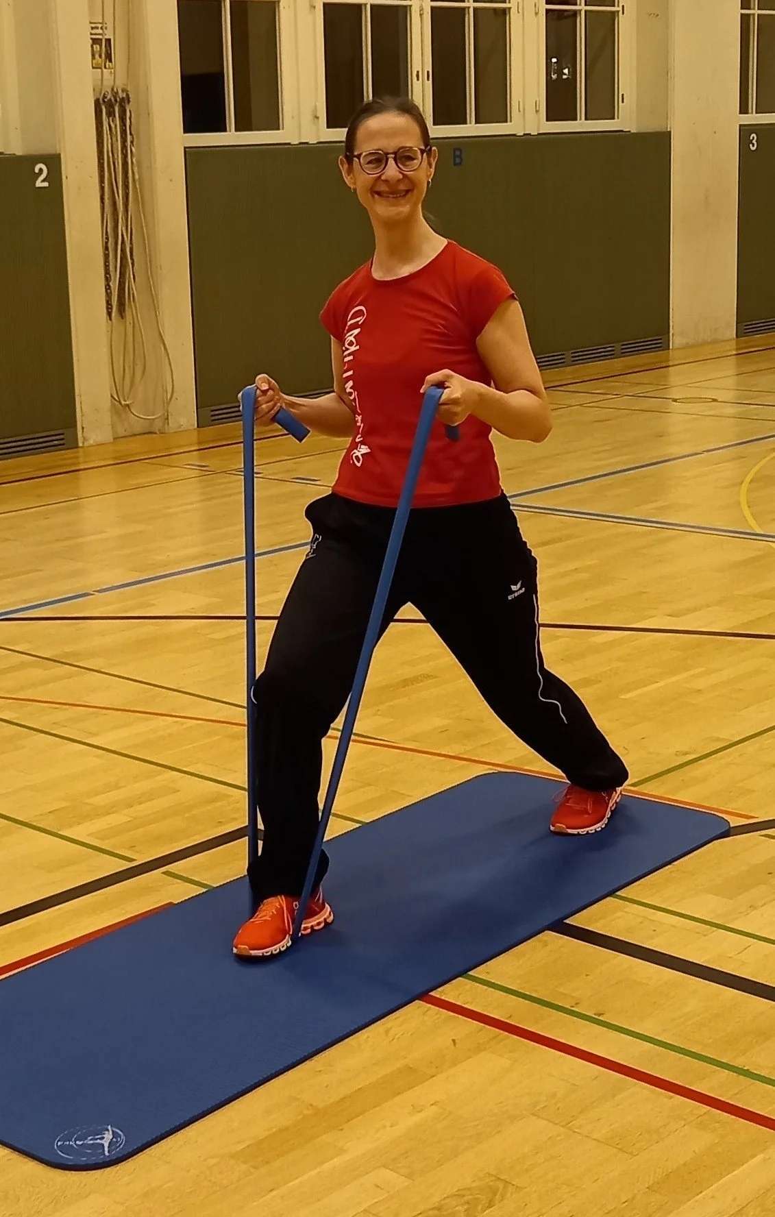 Frau trainiert im Fitnessstudio mit Widerstandsbändern auf einer Gymnastikmatte.