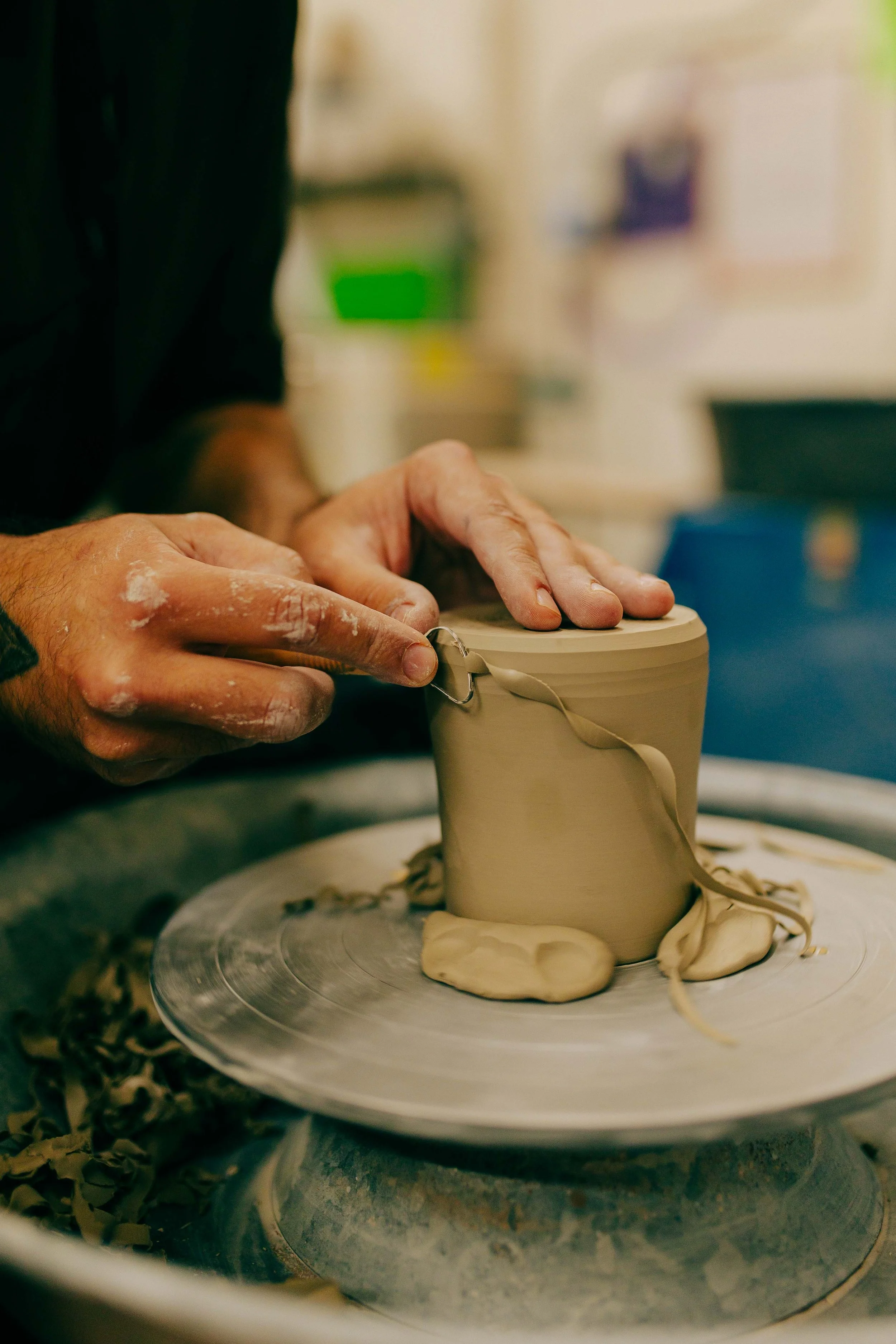Person shaping clay on pottery wheel in a workshop.