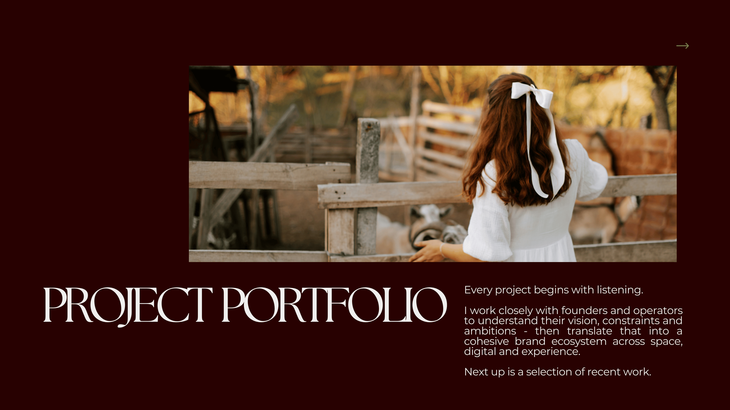 A young girl with long red hair tied with a white ribbon, wearing a white dress, standing behind a wooden fence at a farm, looking at animals and the farm's rustic environment.