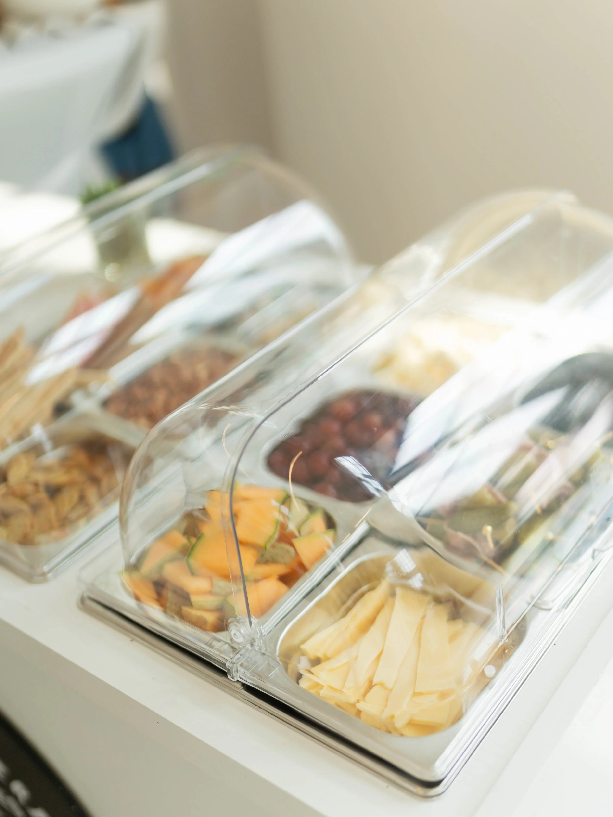 Clear plastic containers with sliced fruits, including cantaloupe, grapes, and other assorted fresh fruits.