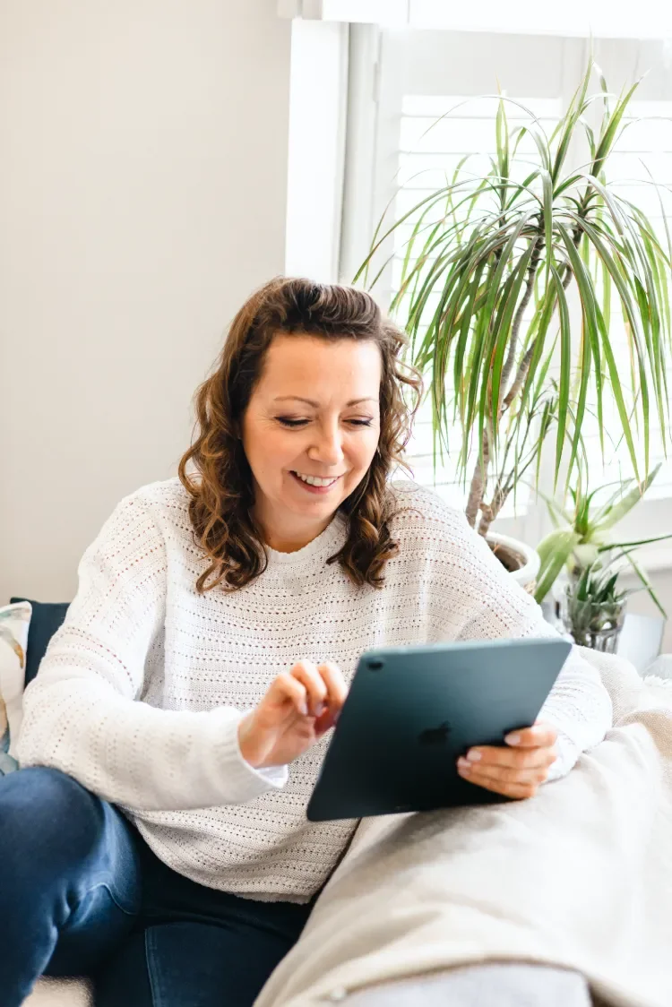 Web designer Sammy Phillips holding a blue iPad sitting on sofa