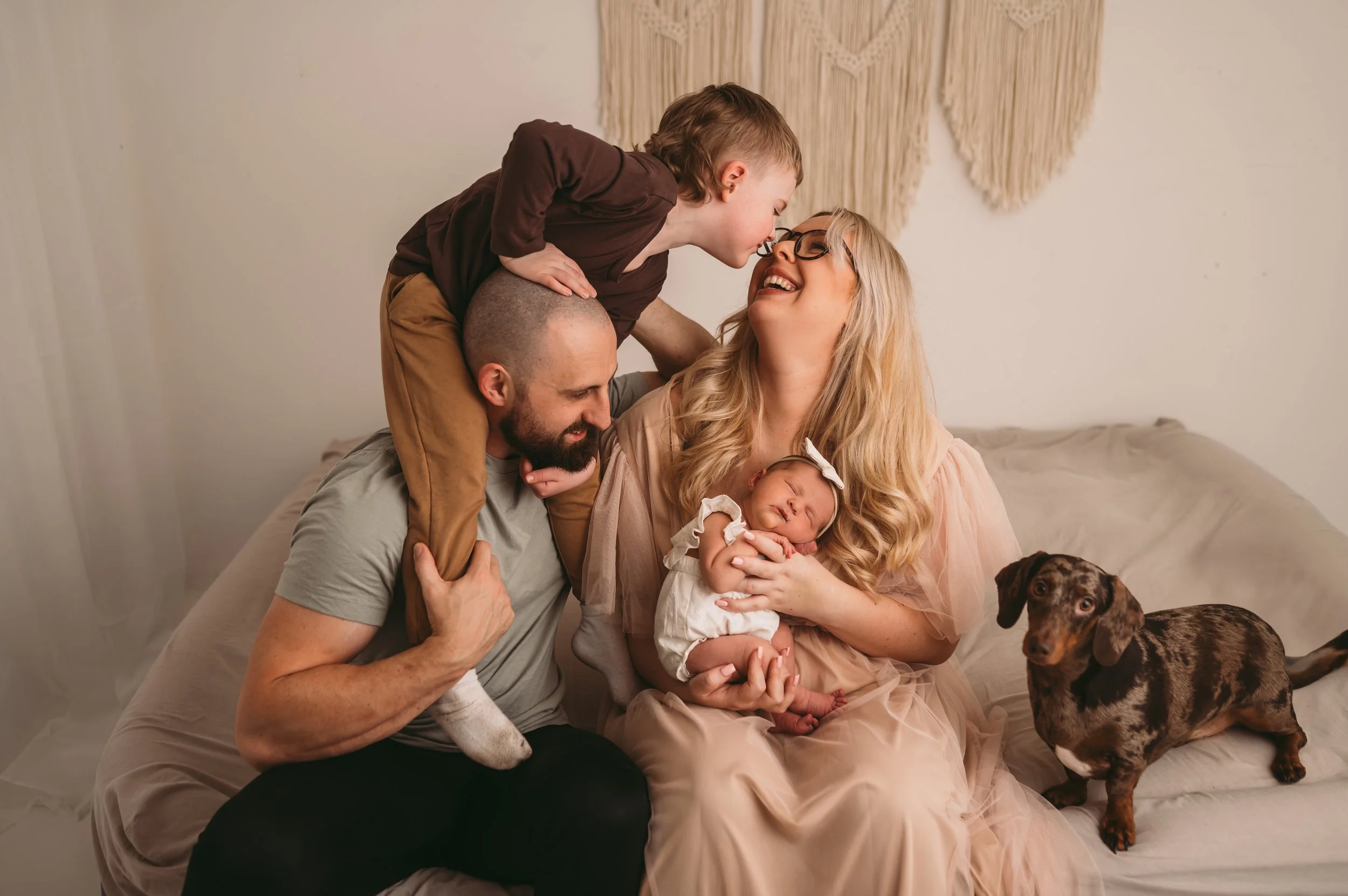 a family of 4 and a dog, smiling and laughing whilst posing newborn girl for a family portrait, Trowbridge, Wiltshire