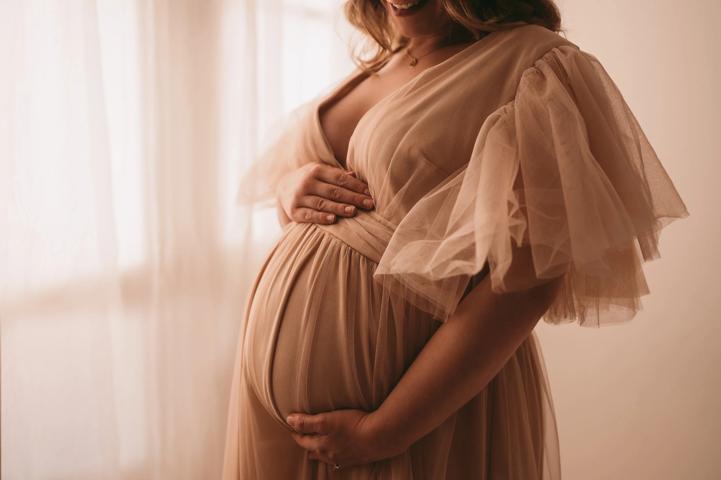 Close up of a woman holding her baby bump wearing a tulle dress, used with KP-Photos customer wardrobe, based in Trowbridge, Wiltshire